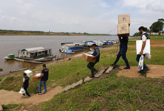 Personal electoral carga máquinas de voto y material electoral para llevar por barco a centros de votación, el día antes de la segunda vuelta de las presidenciales en Autazes, estado de Amazonas, Brasil, el sábado 29 de octubre de 2022.