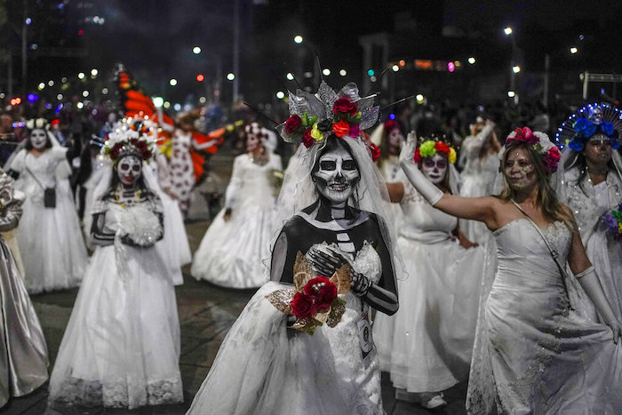 Personas vestidas como las icónicas "Catrinas" de México marchan en la Gran Procesión de las Catrinas, parte de las próximas celebraciones del Día de Muertos en la Ciudad de México, el domingo 23 de octubre de 2022.