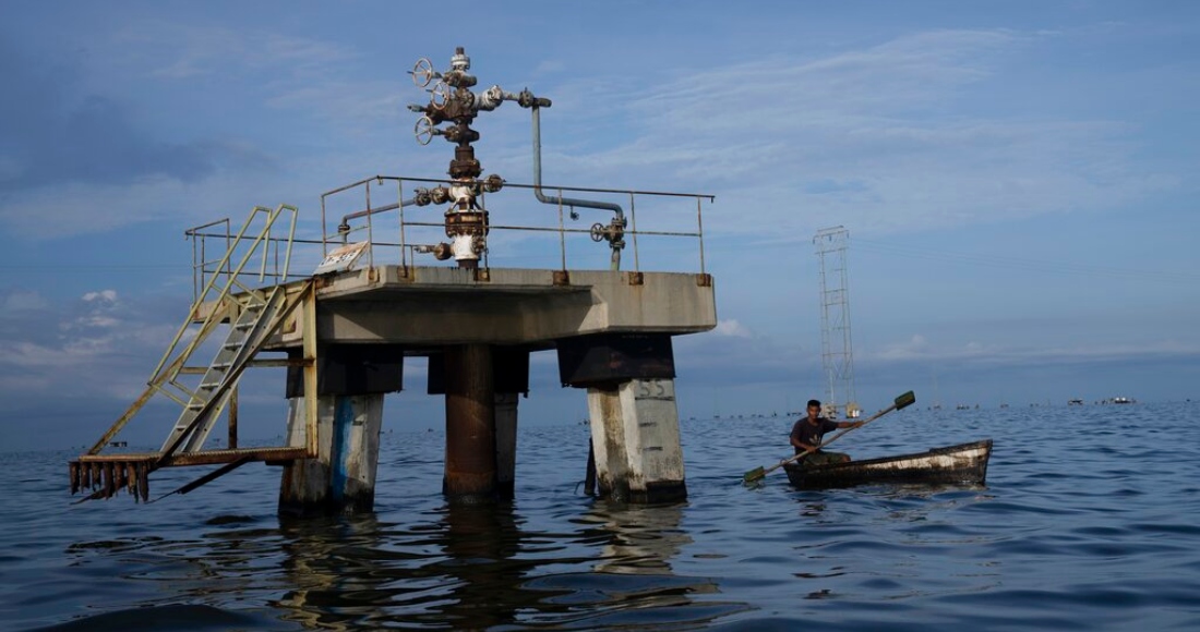 En esta imagen de archivo, un pescador pasa junto a una sonda de petróleo inactiva en el lago Maracaibo, en Venezuela, el 12 de octubre de 2022.