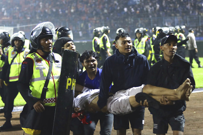 Un grupo de aficionados carga a un hombre herido en los enfrentamientos durante un partido de futbol en Malang, Indonesia, el sábado 1 de octubre de 2022.