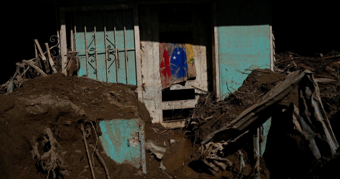 Una bandera venezolana cuelga en una casa llena de lodo donde continúa la búsqueda de cadáveres después de las inundaciones de Las Tejerías, Venezuela, el lunes 10 de octubre de 2022.