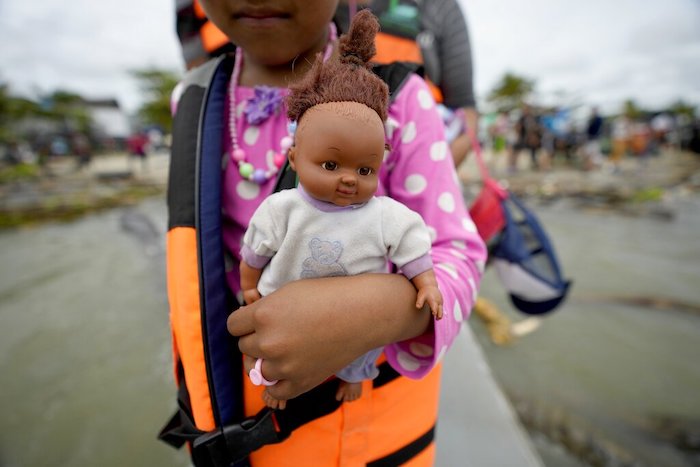 Una niña venezolana, con una muñeca en brazos, camina hacia una lancha que la llevará, junto a otros migrantes, a Acandi, desde Necocli, Colombia, el 13 de octubre de 2022.