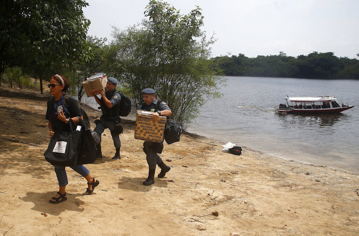 Una trabajadora electoral y policías militares llegan con equipo para un centro de votación un día antes de las elecciones generales del país, en Bela Vista do Jaraqui, en Manaos, Brasil, el 1 de octubre de 2022.