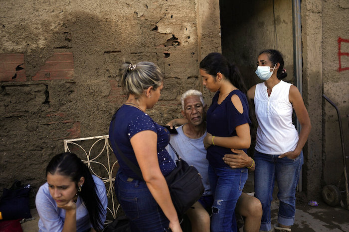 José Medina, centro, abraza a su nieta Enderly mientras los vecinos esperan afuera de la casa de su familia que se inundó en Las Tejerias, Venezuela, el lunes 10 de octubre de 2022.