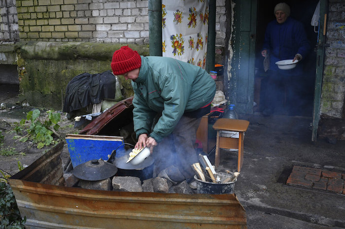 Ancianas cocinan en una hoguera en el patio de un edificio de apartamentos en Lyman, en la región de Donetsk, Ucrania, el domingo 20 de noviembre de 2022.