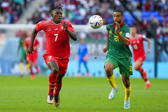 Breel Embolo (izquierda), de Suiza, corre detrás del balón con el camerunés Jean-Charles Castelletto durante el juego del Grupo G que enfrentó a ambas naciones, en el estadio Al Janoub, en Al Wakrah, Qatar, el 24 de noviembre de  2022.