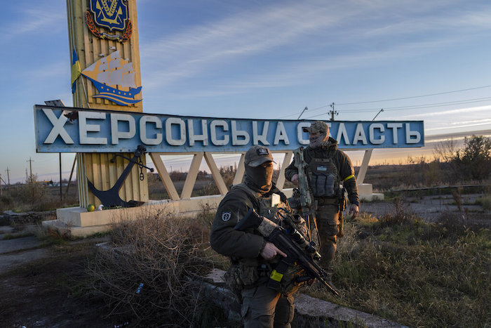 Dos miembros de las fuerzas de defensa ucranianas están parados junto a un letrero que dice "región Jersón" en las afueras de Jersón, sur de Ucrania, el lunes 14 de noviembre de 2022.