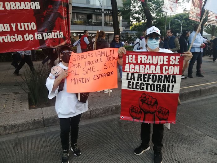 Una mujer sostiene un cartel con la frase "¡El fraude se acabará con la Reforma Electoral!" durante su participación en la marcha que convocó el Presidente Andrés Manuel López Obrador.