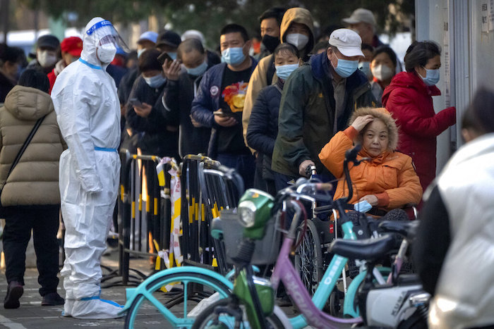 Varias personas, con mascarilla, esperan para someterse a una prueba de detección de COVID-19 en uno de los emplazamientos donde se realizan en Beijing, el 17 de noviembre de 2022.