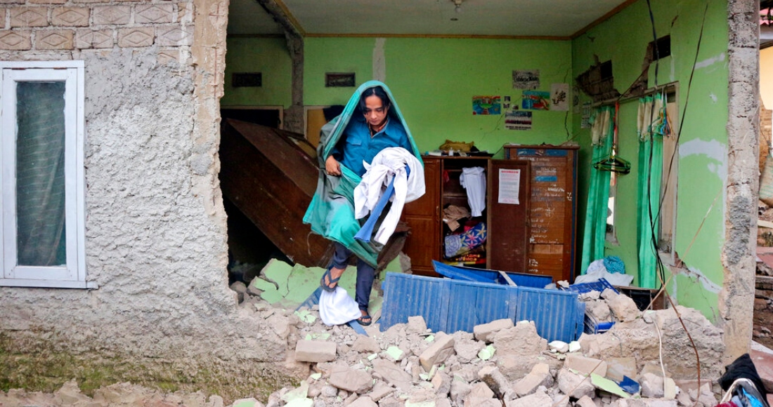 Un hombre recoge ropa de su casa dañada tras un sismo en Cianjur, Java Occidental, Indonesia, el martes 22 de noviembre de 2022.