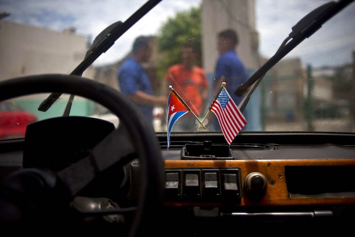 Una bandera cubana y una estadounidense cuelgan del parabrisas de un automóvil estacionado en un garaje en La Habana, Cuba, el 10 de agosto de 2016.