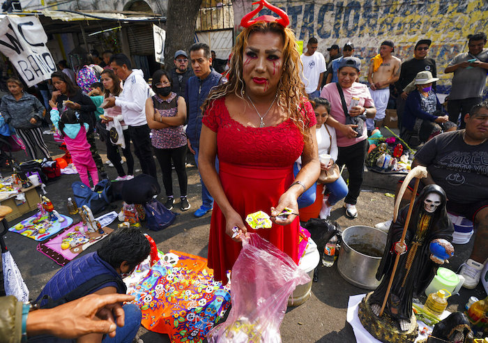 Una creyente regala dulces a quienes esperan para entrar al altar de "La Santa Muerte", en el barrio de Tepito de la Ciudad de México, el martes 1 de noviembre de 2022.