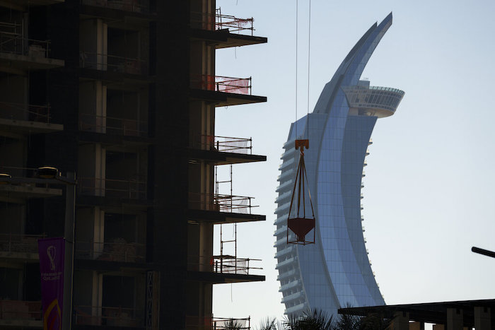 Una grúa trabaja en un edificio en construicción, con las torres con forma de media luna de Lusail en segundo plano, en el centro de Lusail, Qatar, el 24 de noviembre de 2022.