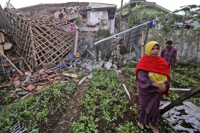 Una mujer camina frente a una vivienda dañada por un sismo en Cianjur, en Java Occidental, Indonesia, el lunes 21 de noviembre de 2022.