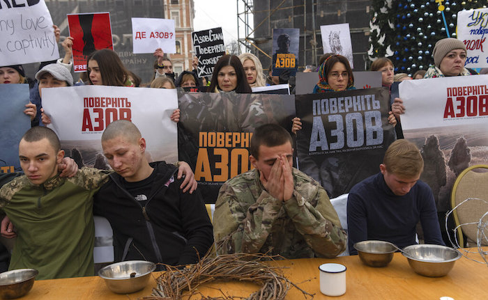 Compañeros de los soldados del Regimiento Azov capturados por Rusia en mayo tras la caída de Mariúpol reclaman su liberación con una mesa de Navidad de estilo carcelario durante una manifestación en Kiev, Ucrania, el sábado 24 de diciembre de 2022.