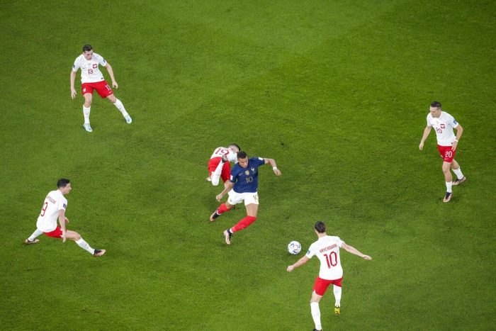 El delantero francés Kylian Mbappé (centro), rodeado de jugadores de Polonia durante el partido por los octavos de final del Mundial, el domingo 4 de diciembre de 2022, en Doha, Qatar.