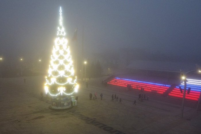 Gente pasa junto a un árbol de Navidad decorado en Mariúpol, en la zona controlada por Rusia en la región de Donetsk, en el este de Ucrania, el sábado 24 de diciembre de 2022.