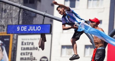 Hinchas argentinos trepan a un poste en Buenos Aires durante los festejos por la coronación en la Copa del Mundo, el domingo 18 de diciembre de 2022.