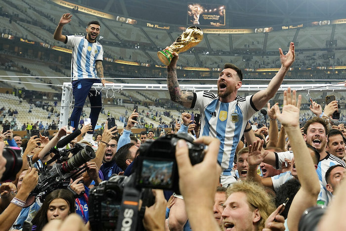 Lionel Messi celebra con el trofeo de campeón mundial con los hinchas de Argentina tras la victoria ante Francia por penales en la final del Mundial, el domingo 18 de diciembre de 2022, en Lusail, Qatar.