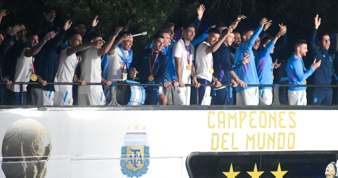 Miembros de la Selección argentina de futbol saludan desde el bus que les lleva a la sede de la Asociación del Futbol Argentino, donde pasarían la noche tras aterrizar en el aeropuerto de Ezeiza, a las afueras de Buenos Aires, Argentina, el martes 20 de diciembre de 2022.