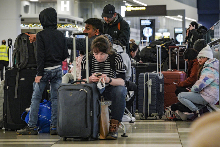 Pasajeros de Southwest Airlines se sientan con su equipaje en la zona de registro debido a retrasos y cancelaciones en el aeropuerto Laguardia, en Nueva York, el viernes 23 de diciembre de 2022.