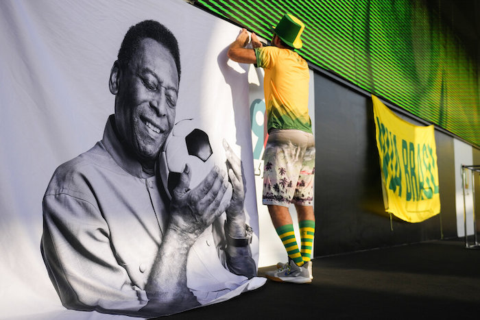 Un aficionado coloca un cartel de apoyo a Pelé en una fiesta de torcedores de Brasil previo al partido contra Corea del Sur en los octavos de final del Mundial, el lunes 5 de diciembre de 2022, en Doha, Qatar.