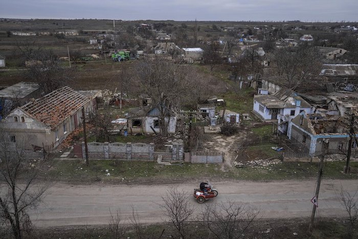 Un hombre en motocicleta pasa el lunes 5 de diciembre de 2022 frente a casas que han sido destruidas durante los enfrentamientos entre las fuerzas rusas y las ucranianas, en Arhanhelske, Ucrania.