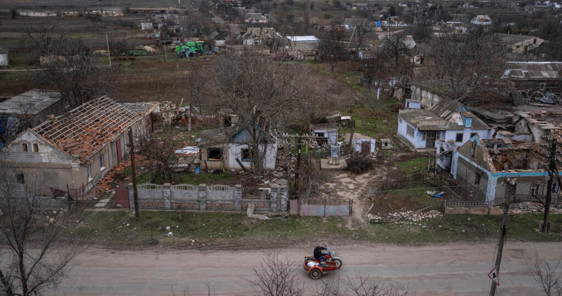 Un hombre pasa en motocicleta ante casas destruidas en los combates entre fuerzas rusas y ucranianas en la localidad recién liberada de Arhanhelske, Ucrania, el lunes 5 de diciembre de 2022.