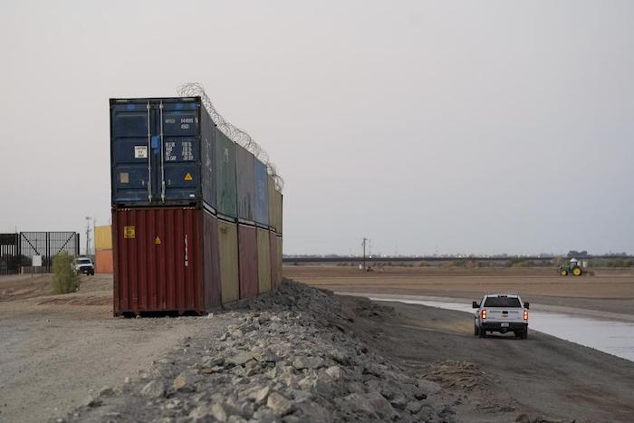 Un vehículo de la Patrulla Fronteriza de Estados Unidos pasa junto a una hilera de contenedores de carga apilados cerca de la frontera con México, el martes 23 de agosto de 2022, cerca de Yuma, Arizona.