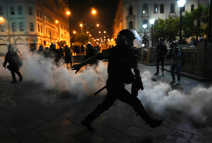 Una nube de gas lacrimógeno rodea a los policías que intentan disipar a simpatizantes del destituido Presidente Pedro Castillo, el domingo 11 de diciembre de 2022, en la plaza San Martín, en Lima.