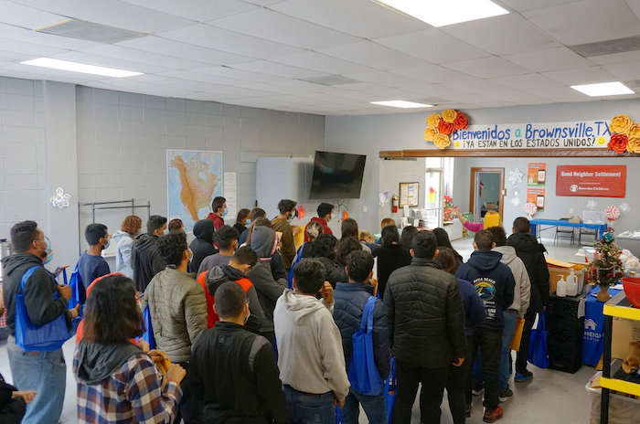 Varias personas hacen filas dentro del centro de bienvenida a migrantes frente a la estación de autobuses, el viernes 16 de diciembre de 2022, en Brownsville, Texas.