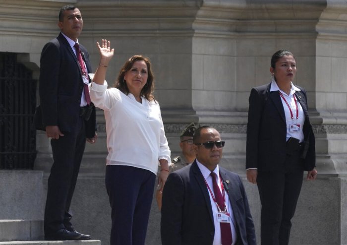 Rodeada de agentes de seguridad, la Presidenta de Perú, Dina Boluarte, saluda a la prensa en el exterior del palacio presidencial, en Lima, Perú, el 10 de enero de 2023.