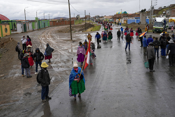 Los residentes caminan a lo largo de una barricada colocada por manifestantes que piden la renuncia de la Presidenta Dina Boluarte y la disolución del Congreso, en Acora, en el sur de Perú, el domingo 29 de enero de 2023.