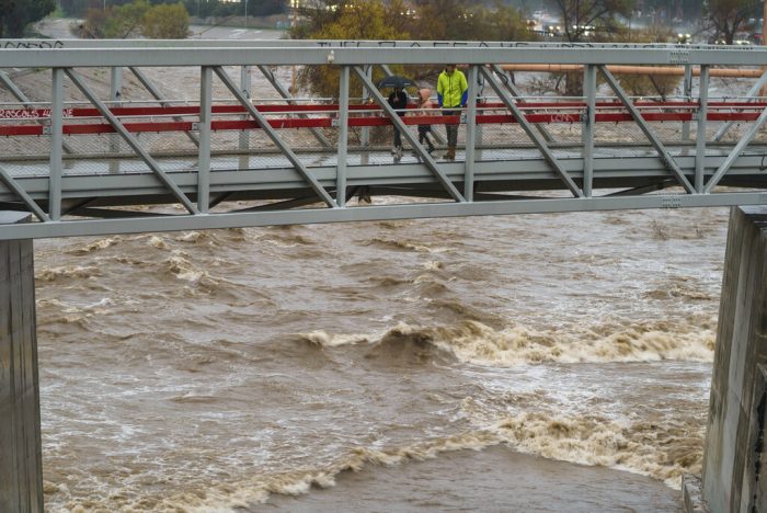 Personas cruzan un puente sobre un crecido río Los Ángeles, el 14 de enero de 2023, en Los Ángeles.