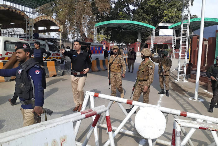 Soldados y policías despejan el acceso para ambulancias al lugar donde explotó una bomba, en una entrada a oficinas policiales en Peshawar, Pakistán, el lunes 30 de enero de 2023. 