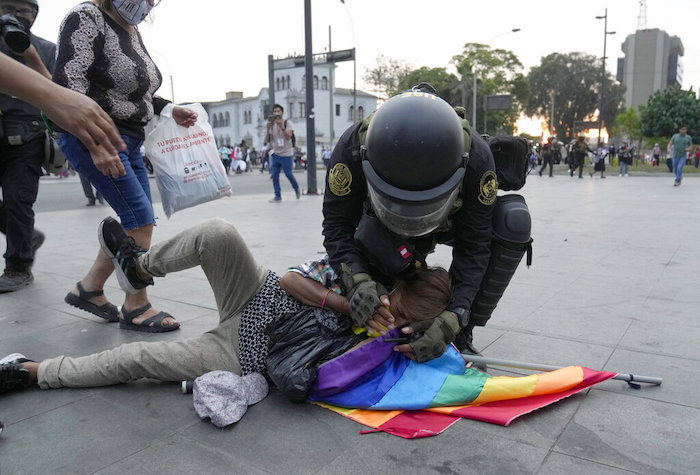 Un agente de la policía antimotines ayuda a un manifestante de oposición afectado por gas lacrimógeno y cayó al suelo, en una marcha contra la Presidenta peruana Dina Boluarte en Lima, Perú, el miércoles 18 de enero de 2023.