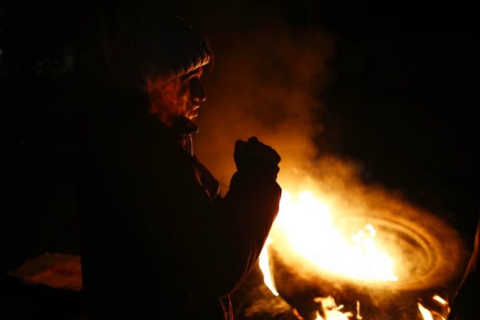 Un indígena frente a una llanta en llamas en un bloqueo de carretera para protestar contra el Gobierno de la Presidenta peruana Dina Boluarte y contra el Congreso en Cusco, Perú, en la noche del jueves 12 de enero de 2023.