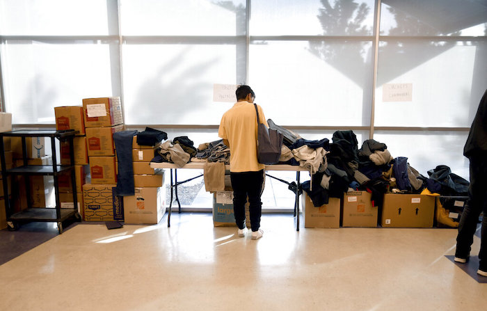 Un migrante busca prendas entre ropa donada en un refugio improvisado en Denver el viernes 6 de enero de 2023.