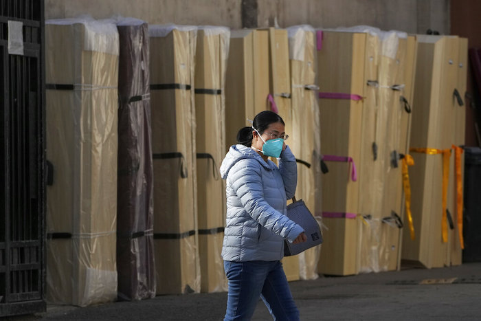 Una mujer con mascarilla pasa junto a ataúdes vacíos almacenados en el exterior de una morgue de un hospital de Beijing, el 6 de enero de 2023.