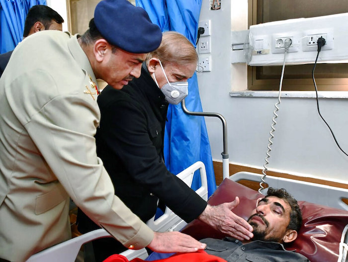 Fotografía proporcionada por el Departamento de Información de Prensa del Primer Ministro de Pakistán Shehbaz Sharif, segundo de la izquierda, y el jefe del ejército, general Asim Munir, consolando a una víctima de un ataque suicida al interior de una mezquita durante su visita al hospital en Peshawar, Pakistán, el lunes 30 de enero de 2023.