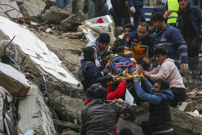 Gente y equipos de rescatistas trasladan a una persona en camilla desde un edificio derruido en Adana, Turquía, el lunes 6 de febrero de 2023.