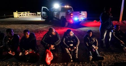 Varios migrantes esperan ser procesados por las autoridades estadounidenses luego de cruzar la frontera de Estados Unidos con México, el 6 de enero de 2023, cerca de Yuma, Arizona.