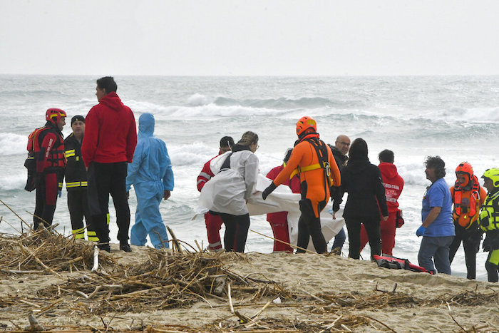 Rescatistas recuperan un cadáver de una playa cercana a Cutro, en el sur de Italia, el domingo 26 de febrero de 2023, después de que un bote de migrantes se partió en un mar picado.