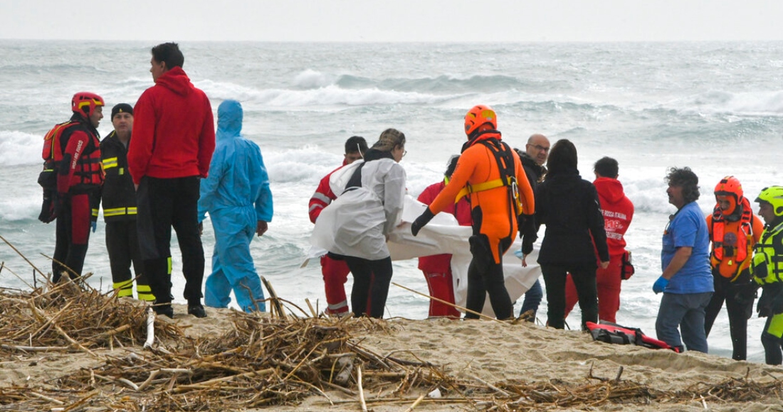 Rescatistas recuperan un cadáver de una playa cercana a Cutro, en el sur de Italia, el domingo 26 de febrero de 2023, después de que un bote de migrantes se partió en un mar picado.