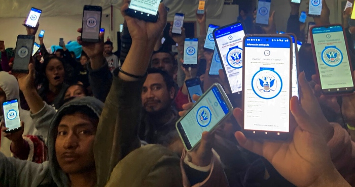 Decenas de migrantes muestran sus teléfonos el domingo 22 de enero de 2023 mostrando en ellos la app CBPOne, en un albergue en Tijuana, México.