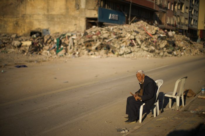 Un hombre se sienta en una silla junto a los escombros de un edificio derruido en la ciudad de Alejandreta, en el sur de Turquía, el martes 14 de febrero de 2023. 