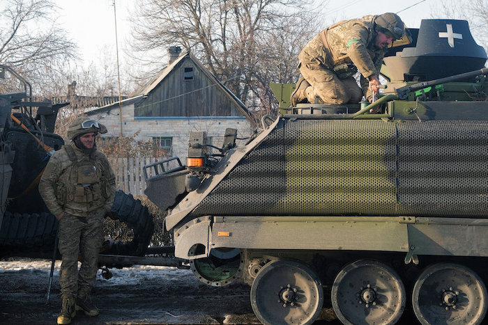 Un soldado ucraniano se ve de pie junto a un vehículo militar en el que trabaja otro soldado, en una calle en la ciudad de Kramatorsk, en la región de Donestk, Ucrania, el domingo 19 de febrero de 2023.