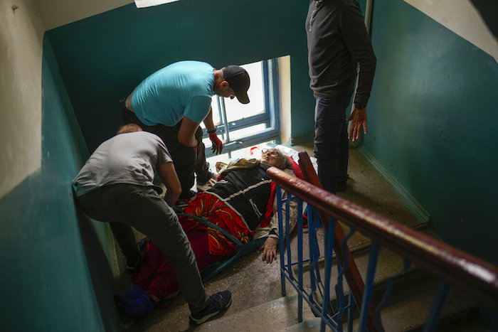 Una mujer es trasladada escaleras abajo desde su casa durante una evacuación realizada por voluntarios del grupo benéfico Vostok SOS en Kramatorsk, en el este de Ucrania, el jueves 26 de mayo de 2022. 