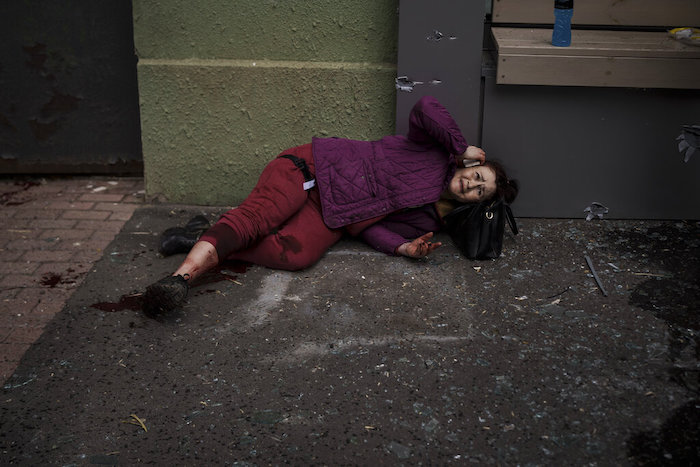 Una mujer herida se ve en el suelo en una vereda durante un bombardeo ruso en Járkiv, el domingo 17 de abril de 2022.