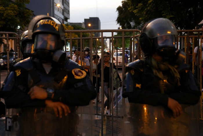 Una mujer mira desde una barrera policial que bloquea una calle que conduce al Congreso en Lima, Perú, el martes 31 de enero de 2023.